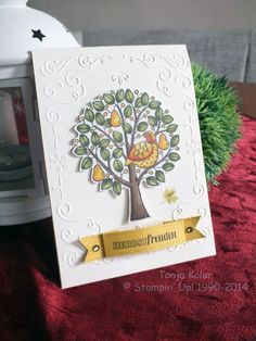 a white card with a tree and fruit on it next to a lit candle holder