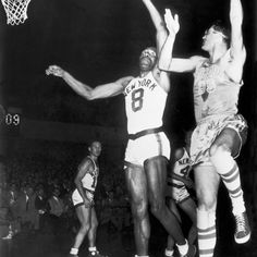 two men are playing basketball in an old black and white photo, one is reaching for the ball