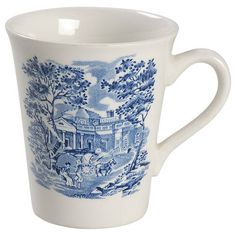 a blue and white coffee cup with an image of a house in the woods on it