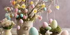 an arrangement of easter eggs and flowers in vases