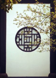 a round metal object on the side of a building with trees in front of it