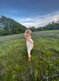 a woman walking through a lush green field