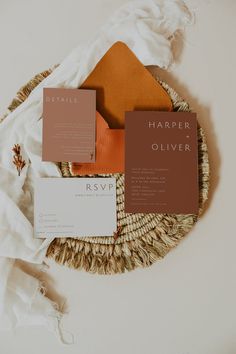 the wedding stationery is laid out on a wicker basket with two matching cards