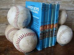 four baseballs sitting next to each other on top of a wooden table with books