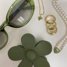 a pair of green sunglasses sitting on top of a table next to pearls and other accessories