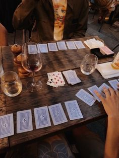 people sitting at a table with playing cards and wine glasses on top of the table