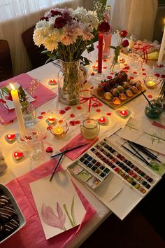 a table topped with lots of different types of flowers and candles on top of it