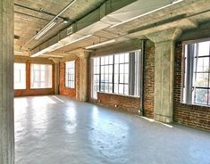 an empty room with exposed brick walls and large windows in the center is seen from across the room