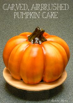 an orange pumpkin on a plate with the words carved, airbrushed pumpkin cake