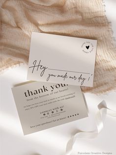 a thank you card with a white ribbon on top of it next to a piece of paper