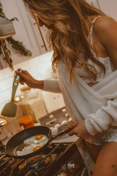 a woman cooking food in a frying pan on the stove