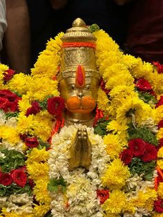 a golden statue surrounded by yellow and red flowers