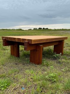 a wooden bench sitting on top of a grass covered field next to a green field