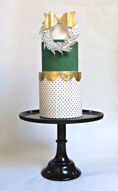 a three tiered cake decorated with gold and white polka dots on a black stand