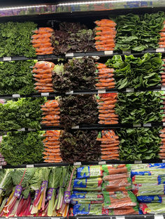 an assortment of vegetables on display in a grocery store, including carrots, lettuce and broccoli