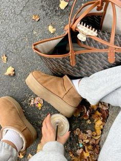 a person sitting on the ground next to a purse and shoes with their feet up