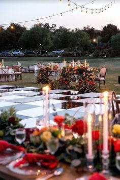 an outdoor dinner table set up with flowers and candles