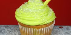 a cupcake with green frosting and a yellow straw sticking out of the top