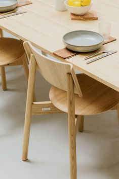 a wooden table with plates and silverware on it, next to a bowl of lemons