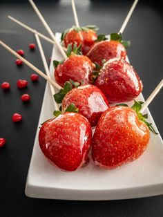 strawberries are arranged on skewers and placed on a plate