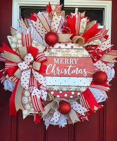 a red and white christmas wreath hanging on the front door