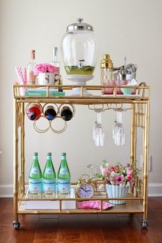 a gold bar cart with drinks and glasses on it's top shelf for sale