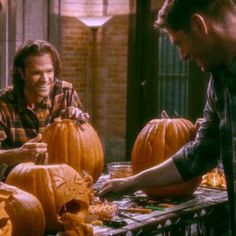 two men are carving pumpkins for halloween