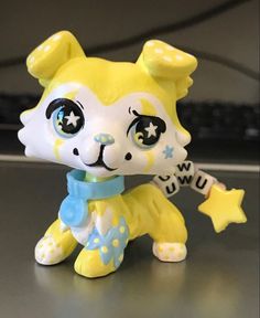 a yellow and white cat figurine with stars on it's chest holding a star