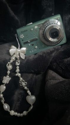 a camera with a chain attached to it's body and some beads around the neck