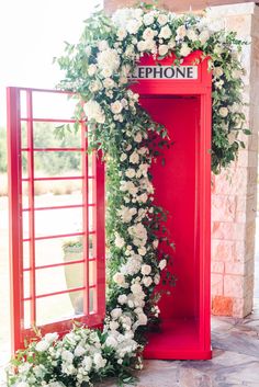 a red phone booth decorated with flowers and greenery