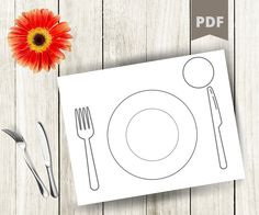 a table setting with utensils, fork and knife on it next to a flower