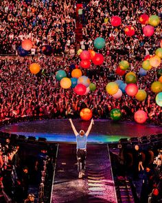 a man standing on top of a stage with lots of balloons in front of him