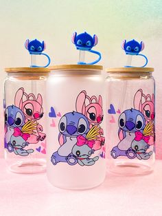 three glass tumblers with cartoon characters on them sitting next to each other in front of a pink background