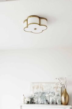 a living room with a white fireplace and gold vases on top of the mantel