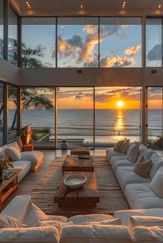 a living room filled with white couches next to a large window overlooking the ocean