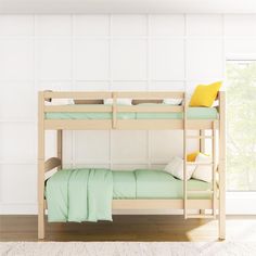 a wooden bunk bed with green sheets and pillows on the bottom level, against a white wall