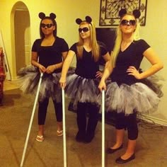 three women dressed up as mickey mouses with crutches in front of them