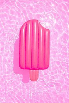 an ice cream popsicle floating on top of a pink pool