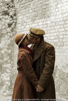 a man and woman standing next to each other in front of a brick wall