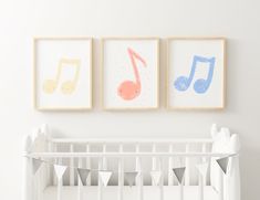 three framed musical notes hang on the wall above a crib