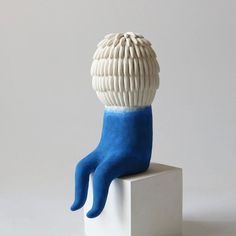 a blue and white sculpture sitting on top of a block of cement with one foot up