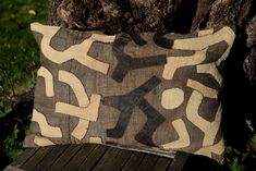 a brown and black pillow sitting on top of a wooden bench next to a tree