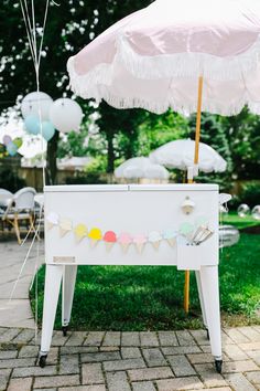 an ice cream stand with umbrellas and balloons