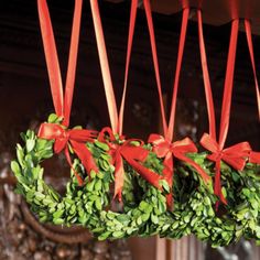 a wreath hanging from the ceiling with red ribbon around it and some green leaves on top