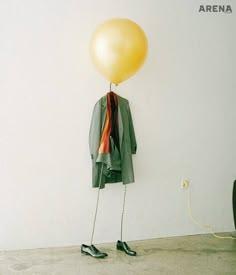 a yellow balloon is hanging from a coat hanger on a wall next to a pair of black shoes