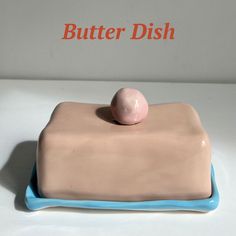 a pink and blue butter dish sitting on top of a white counter next to a red sign