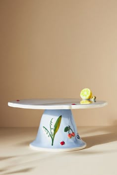 a cake plate with a painted flower on it and a slice of lemon sitting on top