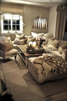 a living room filled with lots of furniture and a lamp hanging over the top of it