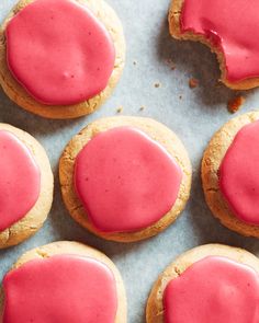 cookies with pink icing sitting on top of a table