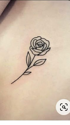 a small rose tattoo on the back of a woman's left side ribcage